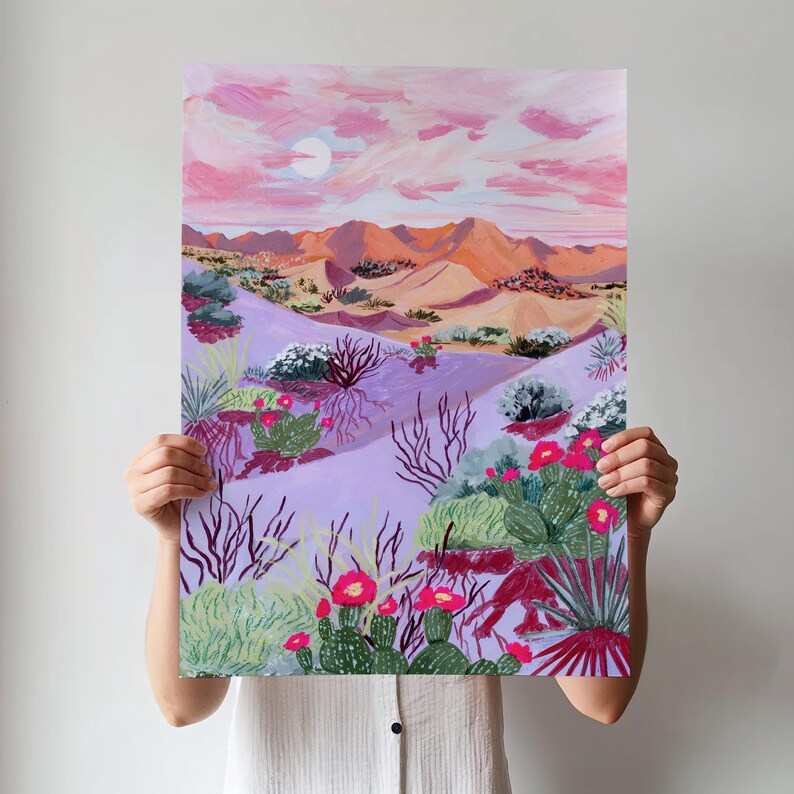 May include: A painting of a desert landscape with a pink sky, a sun, orange mountains, and purple sand dunes. The artwork depicts cacti with red flowers and various desert plants. The colour palette is warm and inviting.