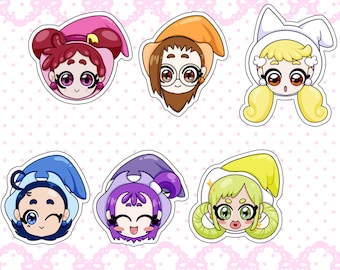 May include: Six colorful cartoon character stickers with different expressions and outfits. The stickers feature characters with witch hats, bunny ears, and other whimsical accessories. The stickers are printed on white paper with a pink polka dot background.