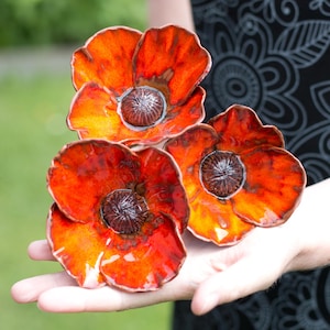 Może przedstawiać: Trzy ceramiczne maki w odcieniach pomarańczowego i czerwonego. Kwiaty są ręcznie robione i mają realistyczny wygląd.