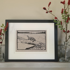 May include: A framed black and white linocut print of a turtle on a log in a lake. The print is titled "Eastern Painted Turtle" and is signed and dated "9/E  2022-11".