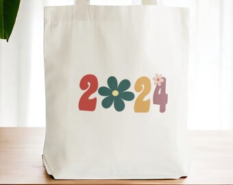 May include: White tote bag featuring a colourful design of the year 2024 with a flower between the 2 and the 4.