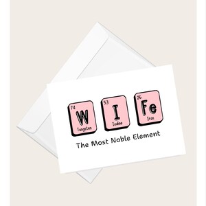 Può includere: Un biglietto di auguri bianco con la parola "WIFE" scritta usando elementi della tavola periodica. Il biglietto è in una busta bianca. Il testo "The Most Noble Element" è sotto la parola "WIFE".