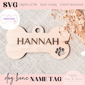 Pode incluir: Uma etiqueta de nome para cão em forma de osso de madeira com o nome "HANNAH" gravado. A etiqueta tem um furo para uma trela e um design de pata.
