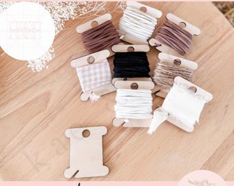 May include: Wooden bobbins with different coloured threads and ribbons. The bobbins are arranged on a wooden surface. The text "wooden BOBBINS" is at the bottom of the image.