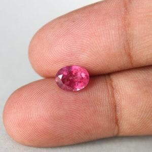 Peut inclure: Une pierre précieuse ovale de couleur rose avec une taille facetée. La pierre précieuse est placée sur un fond neutre.