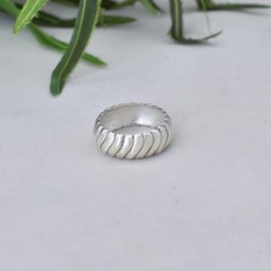 Peut inclure: Une bague en argent avec une bande texturée ondulée.