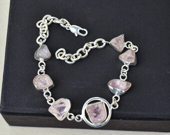 May include: A silver chain bracelet with six pink rose quartz stones. The stones are irregularly shaped and have a natural, raw look. The bracelet has a clasp closure.