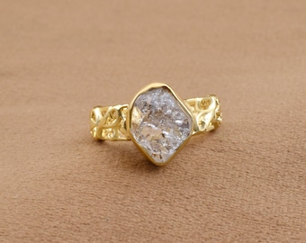 May include: A gold ring with a large, clear, faceted gemstone set in a delicate, ornate design.