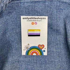 May include: A yellow, white, purple and black enamel pin with a rainbow and a daisy on a white background. The text "emilyslittleshopau" and "@emilyslittleshopau" are printed on the card. The text "Etsy" and an Instagram icon are also printed on the card.
