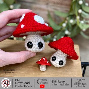 May include: Three crocheted mushroom figures with red caps and white spots, and off-white stems. The mushrooms have large black eyes. The image also includes text that says "PDF Download Crochet Pattern" and "Skill Level: Intermediate".
