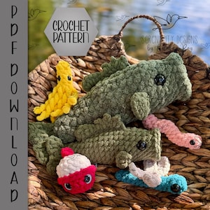 May include: A collection of handmade crochet toys, including two green alligator-like creatures, a yellow octopus, a red and white cupcake, and a pink worm. The toys are displayed in a woven basket. The image includes the text "CROCHET PATTERN".