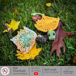 May include: A collection of handmade crochet items, including leaves and small creatures, arranged on a bed of green grass and fallen leaves. The crochet pieces are in various colors, with a focus on autumnal hues. The image also includes text that says "PDF Download Crochet Pattern".