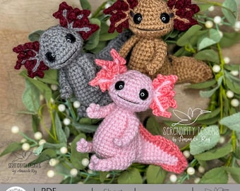 Peut inclure: Trois axolotls crochetés à la main, gris, marron et rose, chacun avec des branchies frangées uniques. Les axolotls sont entourés de verdure. L'image comprend le texte "SERENDIPITY DESIGNS by Amanda Ray" et "PDF Download Crochet Pattern".