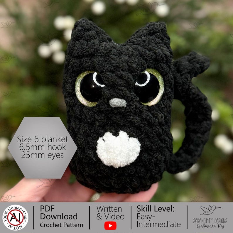 K&ouml;nnte beinhalten: Eine handgefertigte, schwarze H&auml;kelkatzen-Tasse mit gro&szlig;en, glitzernden gr&uuml;nen Augen und einer wei&szlig;en Brust. Die Tasse hat einen Henkel. Das Bild enth&auml;lt den Text "Size 6 blanket, 6.5mm hook, 25mm eyes".
