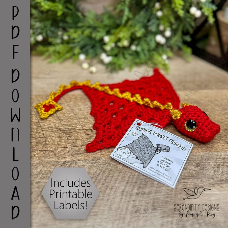 May include: A handmade red crochet dragon with yellow accents and large black eyes. The dragon has a tag that reads "Gliding Pocket Dragon" and "Includes Printable Labels!" on a wooden surface.