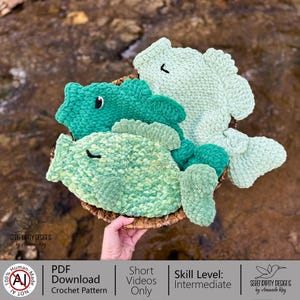May include: A collection of three handmade crochet fish in shades of green, displayed in a woven basket. The fish have detailed fins and eyes, with varying textures. The image includes text that says "PDF Download Crochet Pattern" and "Skill Level: Intermediate".