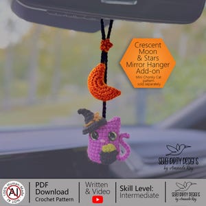 Peut inclure: Une suspension en crochet pour rétroviseur de voiture représentant un chat violet portant un chapeau de sorcière et tenant un chaudron, suspendu par un cordon noir avec un croissant de lune orange et une étoile. Texte : Crescent Moon & Stars.