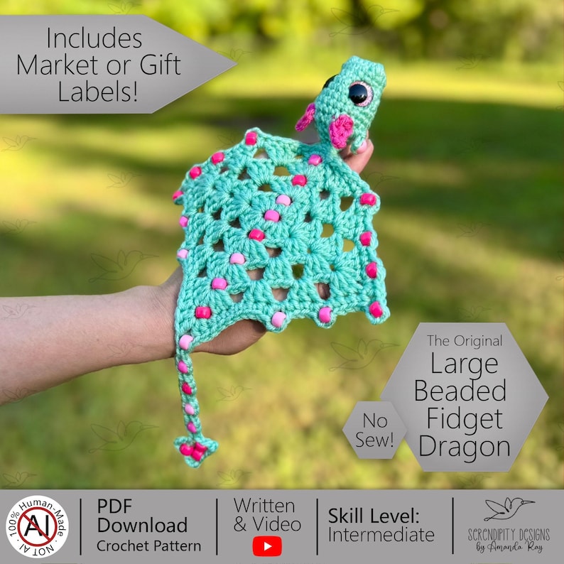 May include: A turquoise crocheted dragon with pink accents and beaded details. The dragon has large eyes and a long tail. The text on the image says "The Original Large Beaded Fidget Dragon".