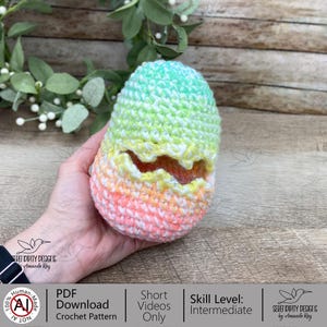 May include: A crocheted egg in pastel shades of pink, orange, yellow, and green. The egg features a jagged opening. The text "PDF Download Crochet Pattern" is visible.