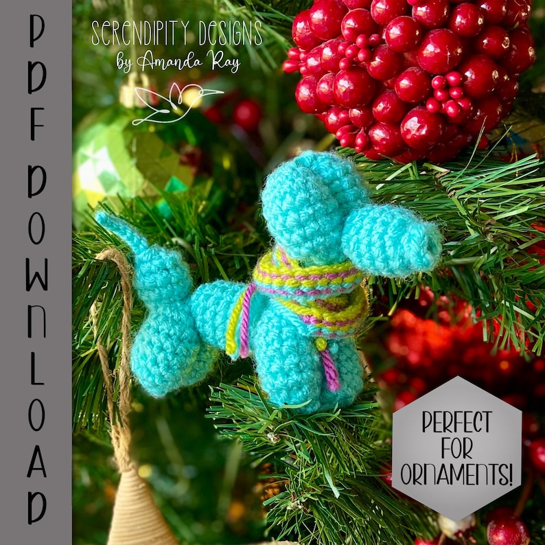 May include: A turquoise crocheted balloon animal ornament with a striped scarf, hanging on a Christmas tree. The ornament has a long trunk and a tail. The text "Serendipity Designs by Amanda Ray" is at the top. The text "PDF DOWNLOAD" is on the left side.