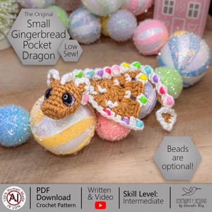 May include: A handmade crocheted gingerbread dragon with brown and white details, and colourful bead accents. The dragon is on a glittery ball. Text on the image reads "Small Gingerbread Pocket Dragon" and "Beads are optional!"