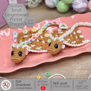May include: Two crocheted gingerbread pocket dragons with white detailing and colourful bead accents are shown on a pink plate. The dragons have large, black eyes and are labelled "The Original Small Gingerbread Pocket Dragon". The crochet pattern is available as a PDF download.
