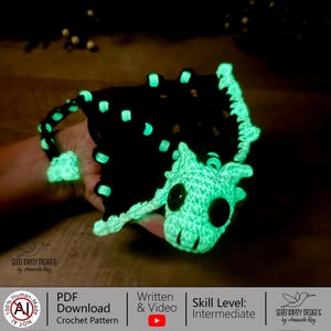 May include: A handmade crochet dragon in black and neon green. The dragon has large black eyes and glowing accents. The image includes text that says "SERENDIPITY DESIGNS by Amanda Ray", "PDF Download Crochet Pattern", and "Skill Level: Intermediate".
