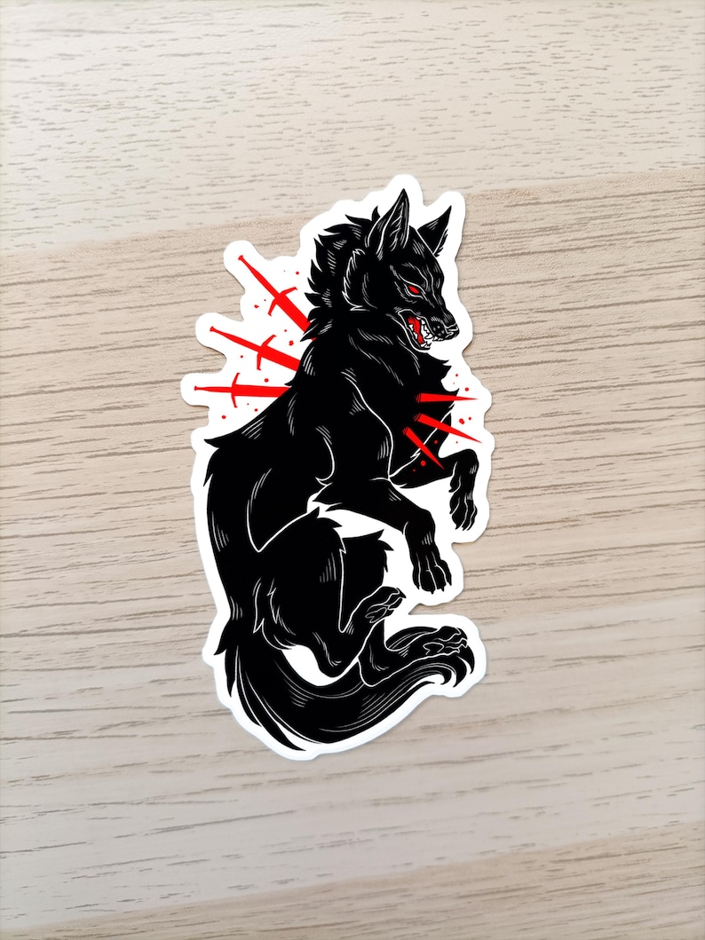 Puede incluir: Pegatina de lobo negro con detalles rojos. El lobo se representa en una pose estilizada y agresiva con ojos rojos y una boca gru&ntilde;ona. L&iacute;neas rojas emanan del cuerpo del lobo, creando un efecto visual impactante. La pegatina tiene un borde blanco.
