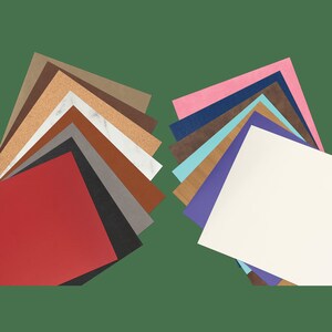 May include: A collection of 18 different colored and textured paper samples. The samples are arranged in two groups, with the top of each group forming a point. The samples include colors such as red, brown, blue, white, and gray.