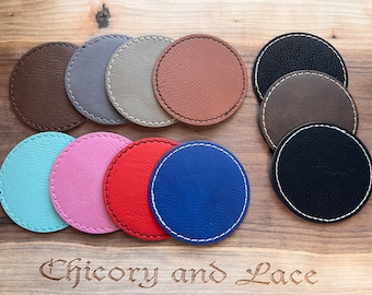 Könnte beinhalten: Eine Sammlung runder Untersetzer in verschiedenen Farben, darunter Braun, Grau, Rosa, Rot und Blau. Jeder Untersetzer hat einen abgesteppten Rand in einer Kontrastfarbe. Die Untersetzer liegen auf einer Holzoberfläche, mit dem Text "Chicory and Lace".