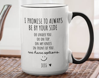 May include: White ceramic coffee mug with a black handle and black rim. The mug has a funny saying that reads "I promise to always be by your side or under you. Or on top. On my knees in front of you. We have options." with a smiley face and the name "Jess" at the bottom.