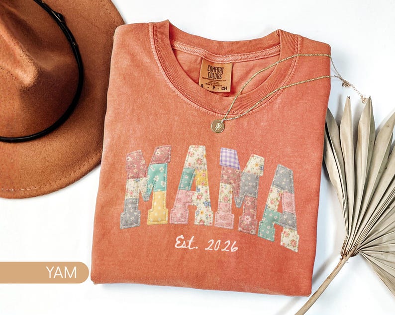Personalized Comfort Colors yam shirt with custom floral patchwork name text, folded flat lay with boho hat and necklace, perfect grandma, nana, mimi, or mama birthday gift tee.