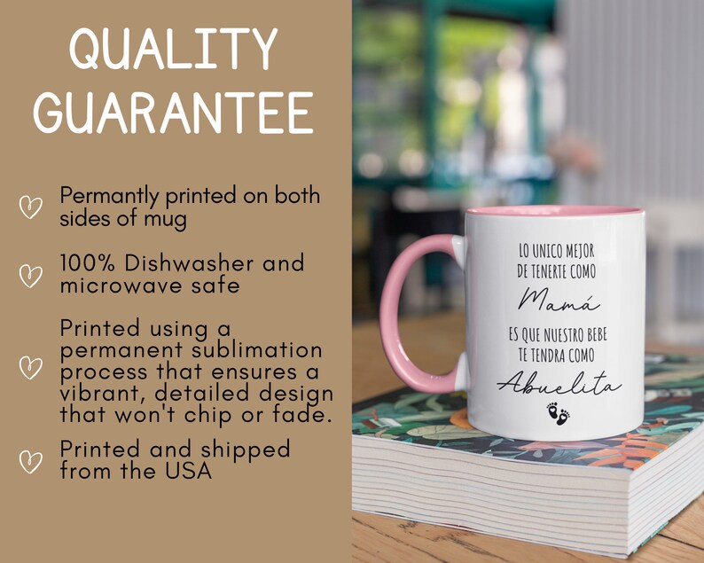 May include: White ceramic mug with a pink rim and handle. The mug has black text that reads "Lo unico mejor de tenerte como Mama es que nuestro bebe te tendra como Abuelita" with a pink footprint graphic. The mug is sitting on a stack of books.