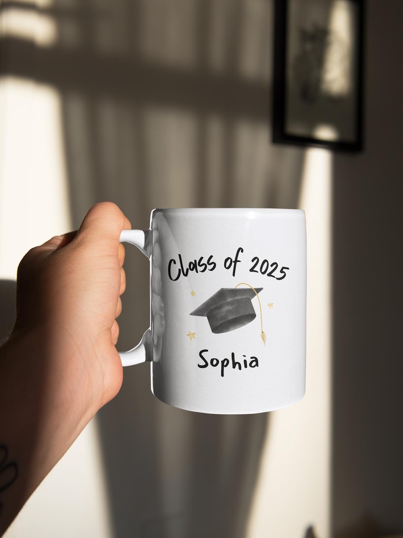 White ceramic mug with a black graduation cap and the text "Class of 2026" and "Sophia" in black.