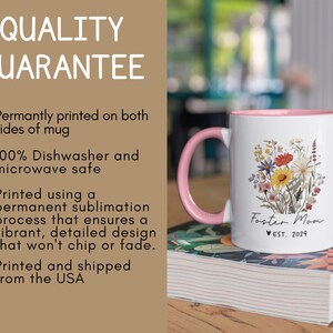 Puede incluir: Una taza de cer&aacute;mica rosa y blanca con un dise&ntilde;o floral y el texto "Foster Mom est. 2024". La taza est&aacute; sobre una pila de libros.