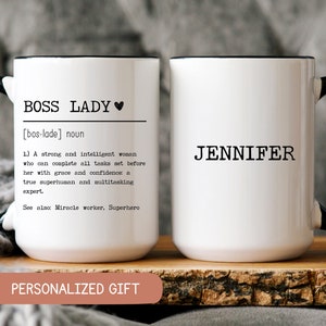 May include: Two white ceramic mugs with black handles and black rims. The mug on the left has the text "BOSS LADY [bos-lade] noun 1.) A strong and intelligent woman who can complete all tasks set before her with grace and confidence: a true superhuman and multitasking expert. See also: Miracle worker, Superhero PERSONALIZED GIFT" The mug on the right has the text "JENNIFER".