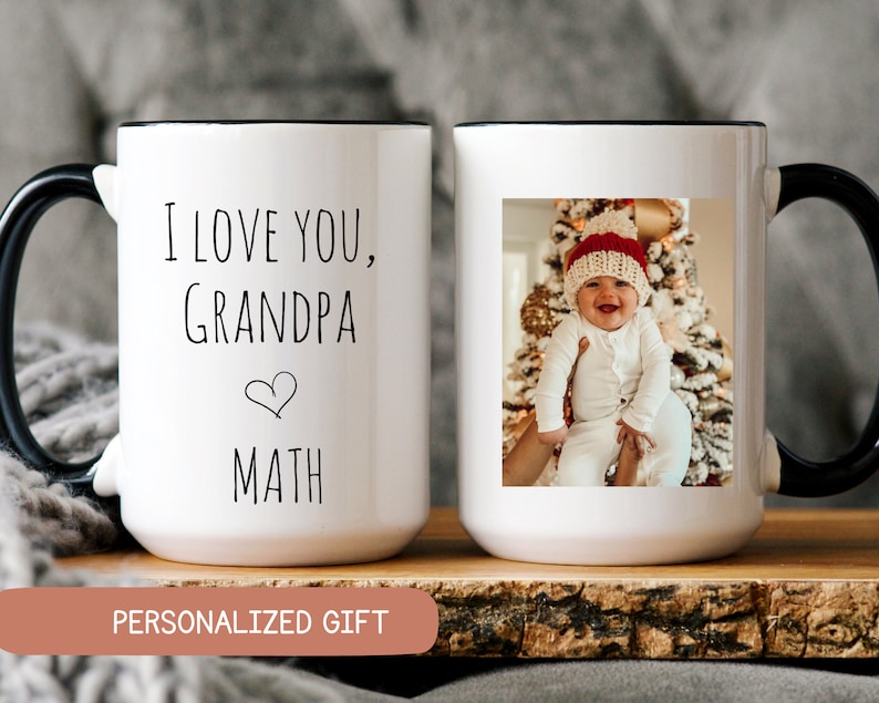May include: White ceramic mug with a black handle and rim. The mug features the text "I LOVE YOU, GRANDPA MATH" and a photo of a baby. The words "PERSONALIZED GIFT" are also visible.