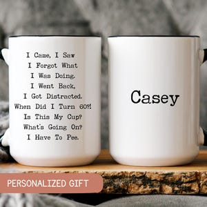 May include: White ceramic mug with black handle and rim. One side features the name "Casey" in black, the other side has humorous text about aging. The mug sits on a wooden surface.