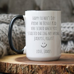 May include: White ceramic coffee mug with a black handle and black rim. The mug has a funny message that reads "Happy Father's Day from the bonus kid you scored when you started dating my mom. Jackpot, right?" with a smiley face and "Love, James" at the bottom.