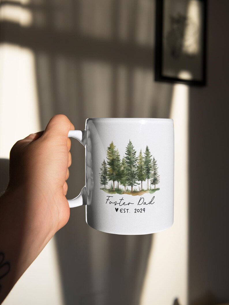 Puede incluir: Taza de cer&aacute;mica blanca con una ilustraci&oacute;n de acuarela de un bosque y el texto "Foster Dad &hearts; EST. 2024"