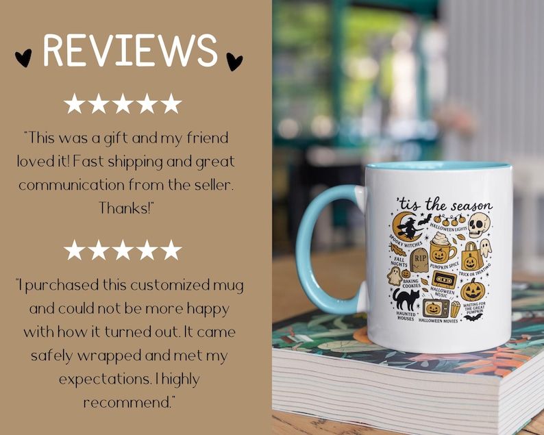 May include: White ceramic mug with a light blue handle and interior. The mug features the phrase "'tis the season" and Halloween-themed illustrations, including a witch, skull, and pumpkin. The mug is sitting on a book.