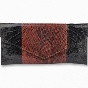 Puede incluir: Un bolso de mano de cuero negro y marrón con estampado de piel de serpiente.