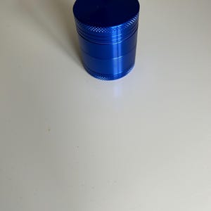 Può includere: Un macinino in metallo blu con quattro sezioni. Il macinino è in alluminio e ha una finitura liscia.