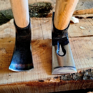May include: Two wooden handled chisels with black metal blades. The chisels are resting on a wooden surface.