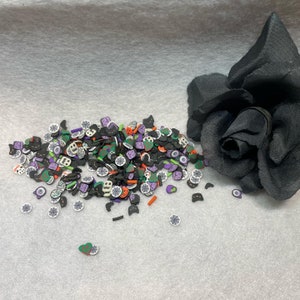 Puede incluir: Un gran surtido de espolvoreados con temática de Halloween en negro, naranja, verde, morado y blanco. Los espolvoreados tienen forma de murciélagos, calabazas, fantasmas, calaveras y ojos.