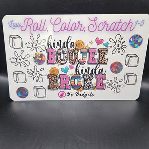 May include: A white board with the text "Roll, Color, Scratch 1-5" written in purple cursive. The board has a colorful design with the words "kinda boujee kinda broke" and a logo that says "B's Budgets".