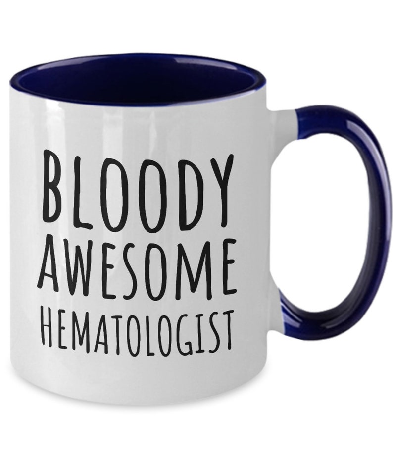 May include: White coffee mug with a blue rim and handle. The mug has black text that reads "BLOODY AWESOME HEMATOLOGIST".