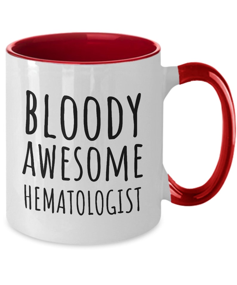 May include: White coffee mug with a red rim and handle. The mug has black text that reads "BLOODY AWESOME HEMATOLOGIST".