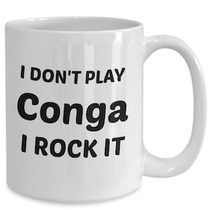 May include: White ceramic coffee mug with black text that reads "I don't play Conga I rock it"