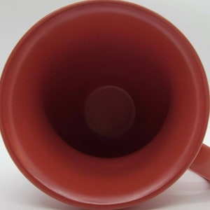 May include: A red ceramic mug with a smooth, glossy finish. The inside of the mug is also red.